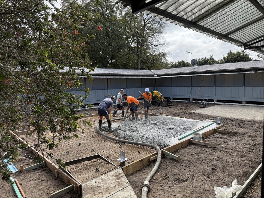 Workman laying concrete in the early phase of the transformation of the centre garden of the Abbey Retreat, Queensland