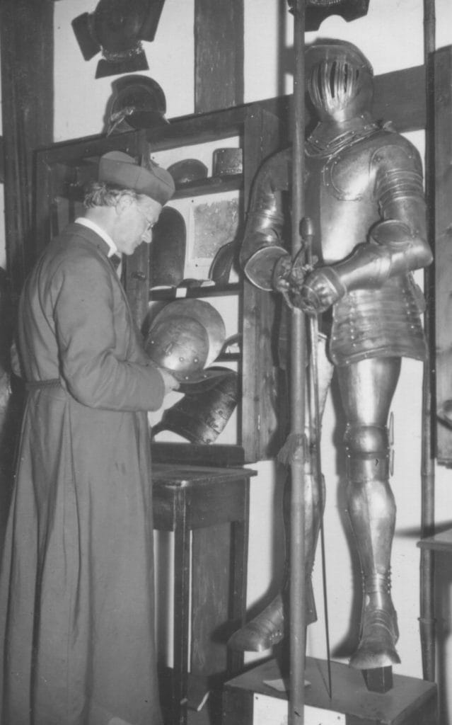 Clergyman viewing medieval armour in a museum collection
