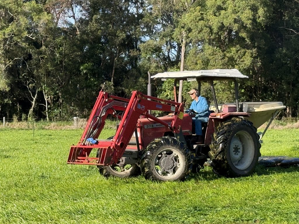 Community member, Fr Paul drives a red tractor maintaining pastures on the Abbey Dairy Farm